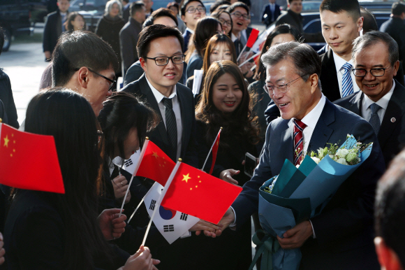 문재인 대통령이 15일 중국 베이징대를 방문해 환영 인사를 나온 한·중 재학생들로부터 꽃다발을 건네받은 뒤 악수하고 있다. 베이징 안주영 기자 jya@seoul.co.kr