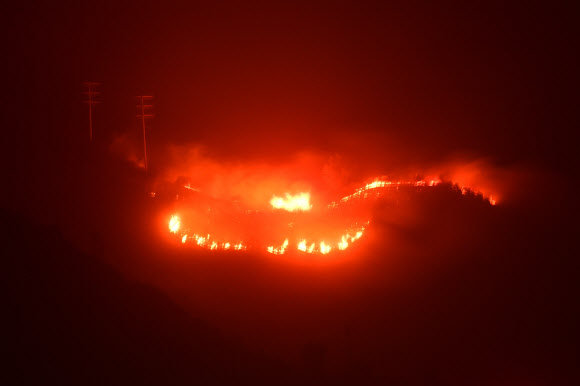 지난 4일(이하 현지시간) 시작된 ‘토머스 산불’이 2주 가까이 맹렬한 기세로 번지고 있는 가운데 16일 미국 캘리포니아주 몬테시토시의 산에 붉은 불길이 피어오르고 있다. AFP 연합뉴스