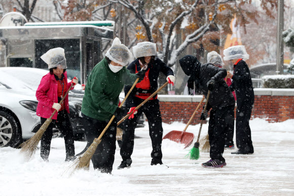 눈 내리는 18일 오전 서울 여의도 한 건물 앞에서 관계자들이 눈을 치우고 있다.  연합뉴스
