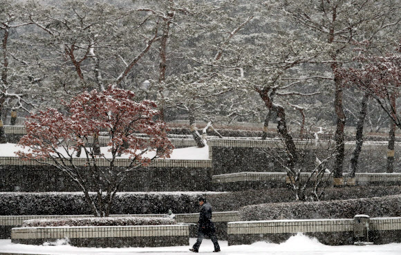 눈이 내린 18일 오전 서초구 서초동에서 시민이 눈을 맞으며 발길을 재촉하고 있다.  연합뉴스