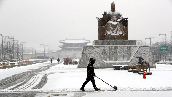 눈이 내린 18일 오전 광화문 광장에서 관계자가 눈을 치우고 있다.  연합뉴스
