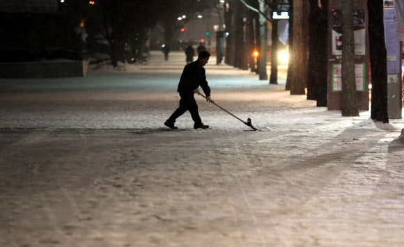 눈이 많이 내린 18일 오전 서울 시내의 한 도로에서 관계자가 제설작업에 여념이 없다. 연합뉴스
