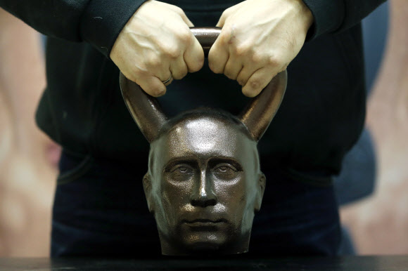 19일(현지시간) 러시아 모스크바에 위치한 운동기구 숍에서 한 남성이 블라디미르 푸틴 러시아 대통령 머리 모양으로 만들어진 케틀벨을 들어보고 있다. TASS 연합뉴스