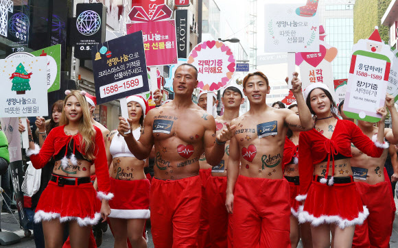 크리스마스를 사흘 앞둔 22일 오후 서울 중구 명동8길에서 ’몸짱산타’들의 장기기증 홍보 퍼레이드가 펼쳐지고 있다.  연합뉴스