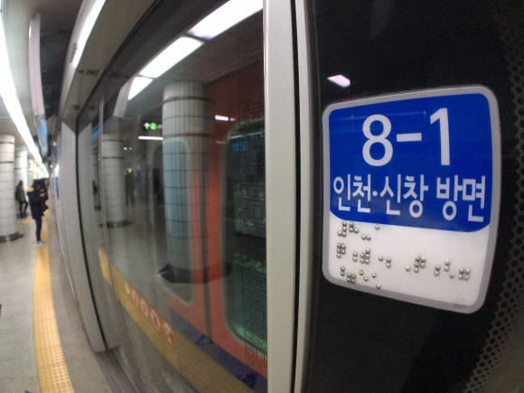 지하철 1호선 시청역 스크린도어에 승강장 번호와 행선지 방향이 적힌 점자 표지가 붙어 있다.