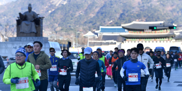 2018년 한 해의 시작을 기념해 개최한 ‘2018 해피뉴런(Happy New Run)’ 10㎞ 마라톤 대회 참가자들이 호흡을 고르며 광화문광장 세종대왕 동상 앞을 힘차게 내달리고 있다. 박지환 기자 popocar@seoul.co.kr
