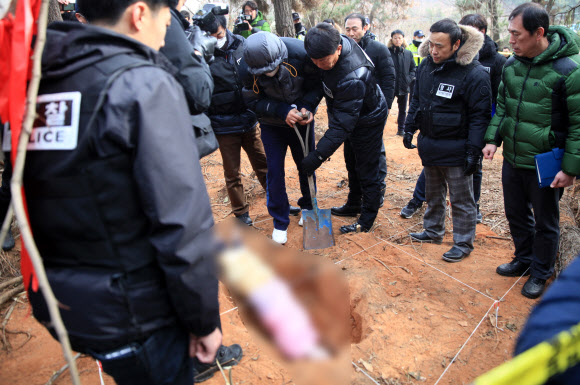 고준희(5)양의 친부가 지난 4일 전북 군산시 내초동 한 야산에서 열린 현장검증에서 준희 양의 시신을 대신해 인형을 묻는 장면을 재연하고 있다.  연합뉴스