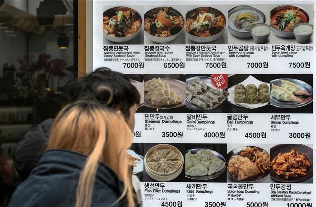 서울 중구 명동의 한 나들이객이 3일 한 음식점 앞에 걸린 가격표를 들여다보고 있다. 뉴스1