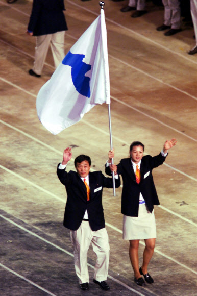 2000년 9월 15일 시드니올림픽 개회식에 공동 기수로 나선 박정철(왼쪽) 북한 유도대표팀 감독과 한국 여자농구 국가대표 정은순이 한반도기를 함께 흔들며 입장하고 있다. AP 자료사진