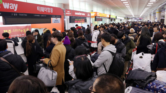 11일 제주공항에 강풍을 동반한 폭설이 내리면서 항공편이 무더기로 결항하자 다른 항공편을 구하려는 관광객들이 항공사 발권 카운터마다 길게 줄을 서서 기다리고 있다. 연합뉴스