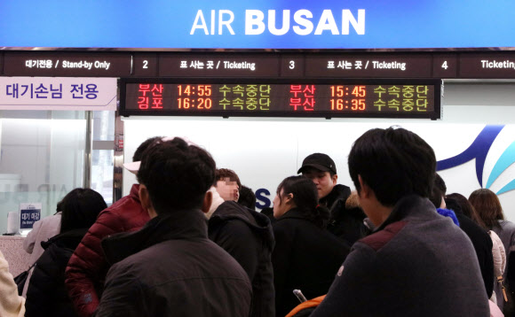 11일 제주공항에 강풍을 동반한 폭설이 내리면서 항공편이 무더기로 결항하자 에어부산이 이용객들에게 전광판을 활용해 수속중단 안내를 하고 있다.  연합뉴스