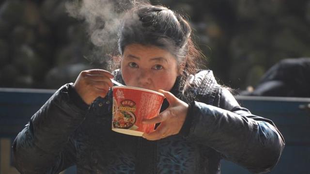 대도시로 유입되는 농민공들의 숫자가 줄면서 중국의 컵라면 소비도 줄고 있다. 사진은 베이징의 여성 농민공이 컵라면을 먹는 모습. BBC중문망 캡처