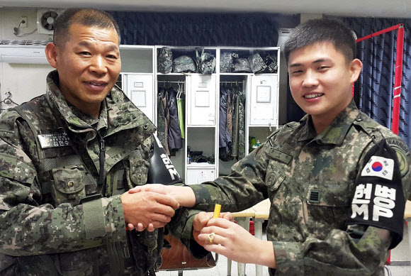 육군 28사단 김만수(왼쪽) 원사가 전역을 앞둔 모범용사에게 도장과 반지를 선물한 뒤 악수하고 있다. 육군 제공