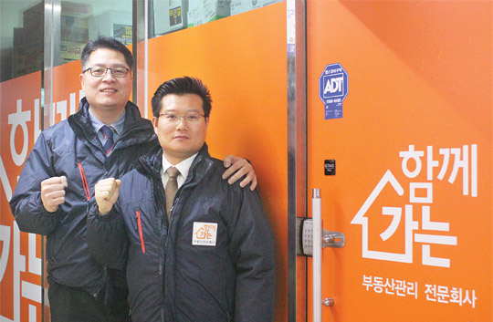 이민구(왼쪽)·김호진 공동대표가 ㈜함께가는 부동산관리 사무실 앞에서 주먹을 불끈 쥐고 있다.