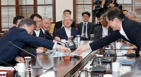 문재인 대통령이 22일 오후 청와대 여민관에서 열린 대통령주재 수석보좌관 회의에서 조국 민정수석으로 부터 과자를 건내 받고 있다. 2018. 01. 22 안주영 기자 jya@seoul.co.kr