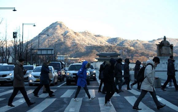 한파가 다시 몰려온 23일 오전 서울 광화문에서 시민들이 잔뜩 웅크린 채 출근하고 있다. 멀리 하얀 눈이 쌓인 북악산이 보인다.   연합뉴스