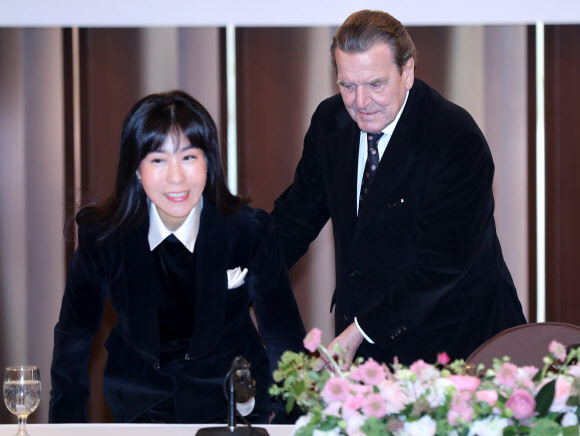 연인 관계를 공식화한 게르하르트 슈뢰더 전 독일 총리가 25일 오전 한국프레스센터 기자회견장에서 자리를 먼저 안내하고 있다.  연합뉴스