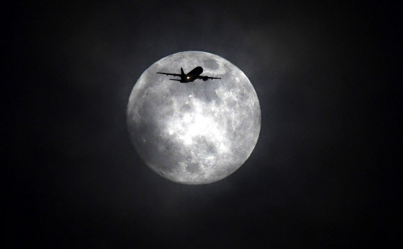 35년 만에 ‘슈퍼문’, ‘블루문’, ‘블러드문’ 총 3가지 천문현상이 일어날 것으로 예견된 31일 영국 런던에서 비행기 한 대가 달을 배경으로 날아가고 있다.  EPA 연합뉴스
