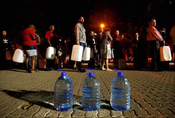 지난달 25일(현지시간) 남아프리카공화국 케이프타운 뉴랜즈 용천수 지역에서 시민들이 생활용수를 확보하려고 물통을 들고 줄 서 있다. 기후변화와 시 당국의 무능으로 케이프타운은 물 공급을 완전 중단하는 ‘데이 제로’(Day Zero)까지 치닫고 있다. 케이프타운 로이터 연합뉴스