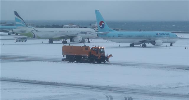 제주지역에 많은 눈이 내린 5일 오전 제주시 제주국제공항 활주로에서 공항 관계자들이 제설작업을 하고 있다. 뉴스1