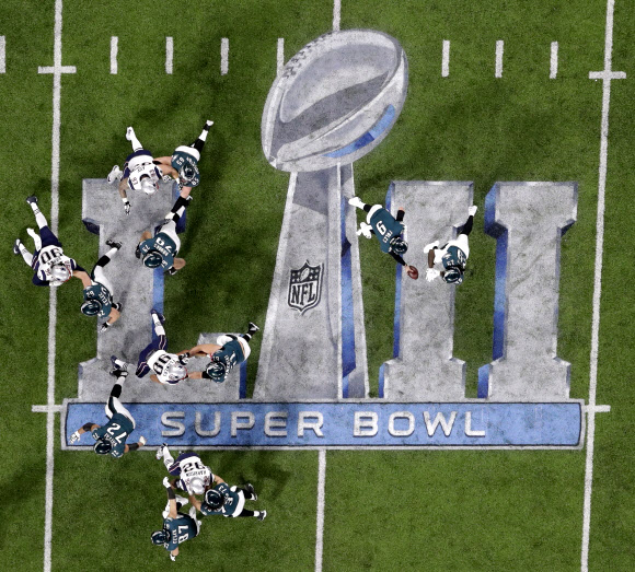 제52회 슈퍼볼 엠블렘이 새겨진 미국 미네소타주 미네아폴리스의 US뱅크 스타디움 그라운드 위에서 첫 우승에 도전하는 필라델피아 이글스와 타이틀 방어에 나선 뉴잉글랜드 패트리어트 선수들이 격돌하고 있다. AP 연합뉴스