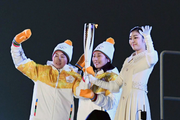 제23회 평창동계올림픽이 9일 막을 올렸다. 사진은 27년 만에 결성된 남북 단일팀 여자 아이스하키 선수인 박종아(가운데)와 정수현(왼쪽)이 성화대 바로 앞에서 성화봉을 든 채 관중에게 손을 흔들고 있다.  평창 박지환 기자 popocar@seoul.co.kr