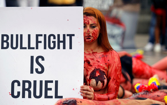 11일(현지시간) 콜롬비아 메델린에서 동물 인권 운동가들이 투우 경기 폐지를 주장하며 온 몸에 가짜 피를 뿌린채 반라로 퍼포먼스 시위를 벌이고 있다. 로이터 연합뉴스