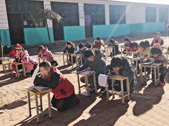 중국 허베이성 바오딩시 취양현의 초등학생들이 난방을 하지 않아 추운 교실을 피해 운동장에서 햇빛을 쬐며 수업을 하고 있다.  북경청년보