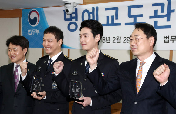 드라마 ’슬기로운 감빵생활’에서 교도관으로 출연한 정웅인, 정경호가 28일 오전 정부과천청사에서 열린 명예교도관 위촉식에서 감사패를 받은 뒤 기념촬영을 하고 있다. 왼쪽부터 이금로 법무부 차관, 정웅인, 정경호, 김학성 교정본부장.  연합뉴스