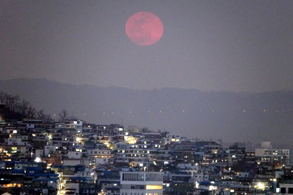 무술년 대보름인 2일 서울시 아차산 위로 붉은 대보름달이 떠오르고 있다. 서울 동쪽의 야경과 붉은색의 대보름달이 아름답게 보인다. 대보름달이 붉게 보이는 것은 지표면에서 가까워서 빛의 파장이 길고 서쪽 하늘로 지는 태양 빛의 영향이다. 달의 붉은빛은 지표면에서 멀어지면서 빛의 파장이 짧아져 하얀색으로 보이게 된다.  연합뉴스