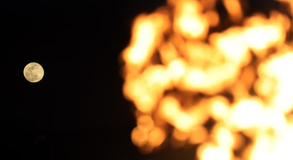 정월대보름인 2일 밤 남산골 한옥마을에서 타는 달집 뒤로 보름달이 보인다.  연합뉴스