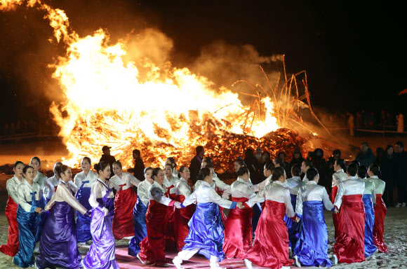정월대보름인 2일 ’해운대달맞이 온천축제’가 열린 부산 해운대해수욕장에서 활활 타오르는 달집을 배경으로 고운 한복을 입은 여인들이 손에 손을 잡고 강강술래 공연을 펼치고 있다. 행사장에는 한 해의 액을 막고 새해 소망을 기원하는 수만 명의 관광객이 운집했다.  연합뉴스