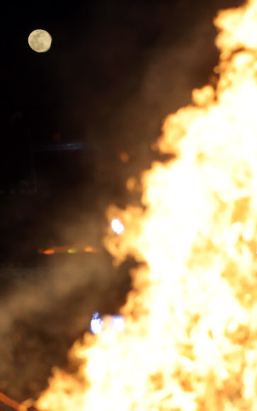 정월대보름인 2일 밤 남산골 한옥마을에서 타는 달집 뒤로 보름달이 보인다.  연합뉴스