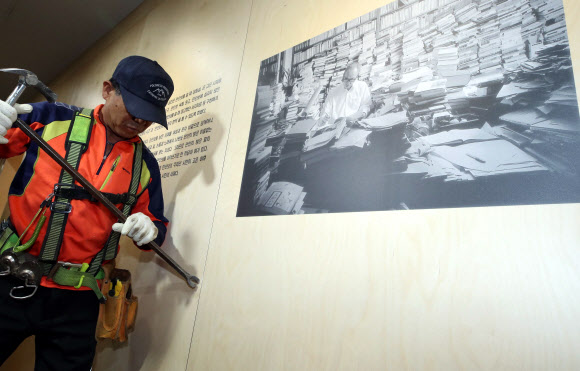 12일 오전 서울도서관에서 관계자들이 성추행 논란에 휩싸인 시인 고은의 작품세계를 조명한 ’만인의 방’ 을 철거하고 있다. 한 작업자가 고은의 사진을 떼어내고 있다.  연합뉴스