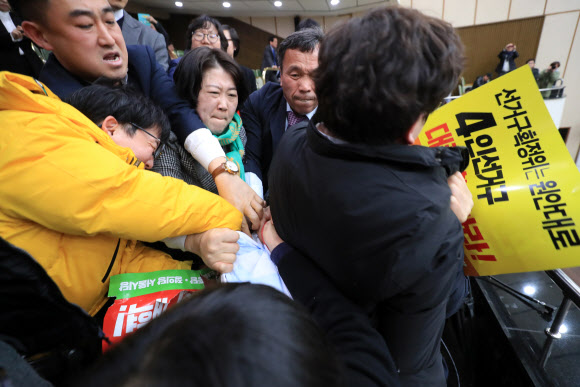 20일 오후 서울시의회 본회의장 방청석에서 정의당, 노동당,녹색당 등 당원들이 4인 선거구 확대 등을 요구하는 내용의 손피켓과 현수막을 펼쳐들자 이를 막는 의회 직원들과 몸싸움을 벌이고 있다.이날 열린 임시회에서는 서울시 자치구의회 의원 선거구와 선거구별 의원정수에 관한 조례 일부 개정조례안이 통과됐다.   연합뉴스