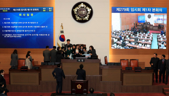 20일 오후 서울시의회 본회의장에서 바른미래당 소속 의원들이 더불어민주당과 자유한국당 소속 의원들 항의 속에 4인 선거구 확대를 요구하며 의장석을 점거한 채 농성을 벌이고 있다. 연합뉴스
