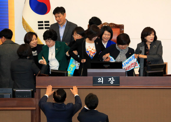 20일 오후 서울시의회 본회의장에서 더불어민주당과 자유한국당 소속 의원들이 4인 선거구 확대를 요구하며 의장석을 점거한 채 농성을 벌이는 바른미래당 소속 의원들을 끌어내고 있다.  연합뉴스