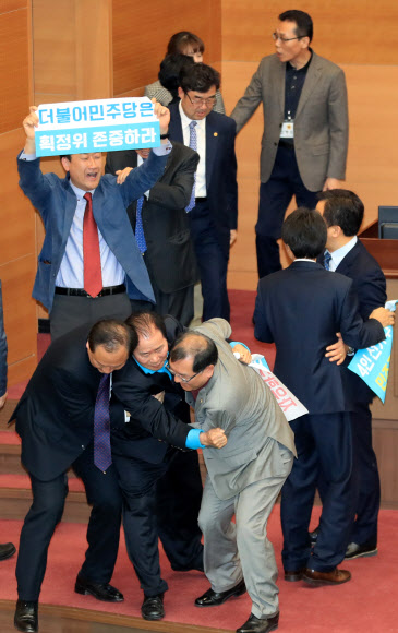 20일 오후 서울시의회 본회의장에서 더불어민주당과 자유한국당 소속 의원들이 4인 선거구 확대를 요구하며 의장석을 점거한 채 농성을 벌이는 바른미래당 소속 의원들을 끌어내고 있다.  연합뉴스