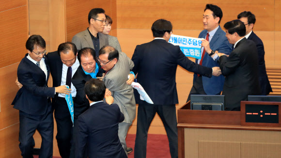 20일 오후 서울시의회 본회의장에서 더불어민주당과 자유한국당 소속 의원들이 4인 선거구 확대를 요구하며 의장석을 점거한 채 농성을 벌이는 바른미래당 소속 의원들을 끌어내고 있다.  연합뉴스
