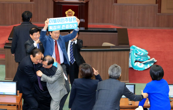 20일 오후 서울시의회 본회의장에서 더불어민주당과 자유한국당 소속 의원들이 4인 선거구 확대를 요구하며 의장석을 점거한 채 농성을 벌이는 바른미래당 소속 의원들을 끌어내고 있다.  연합뉴스