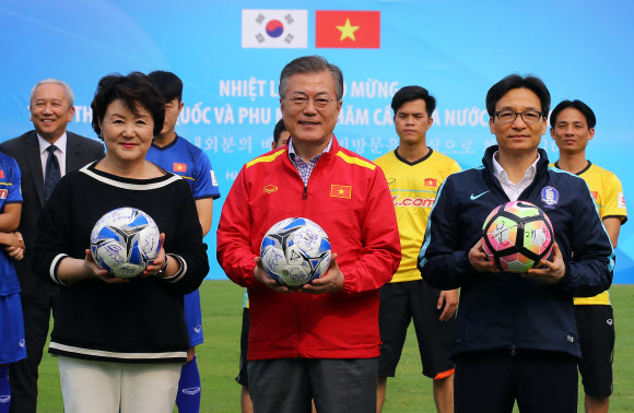 문재인 대통령과 부인 김정숙 여사가 22일 오후 베트남 국빈방문 첫 일정으로 베트남 축구협회를 방문, 부 득 담 베트남 부총리(오른쪽)로부터 베트남 축구 국가대표 선수팀 사인이 담긴 공을 받고 포즈를 취하고 있다. 문 대통령은 대통령과 김 여사 사인이 담긴 공을 선물했다.  연합뉴스