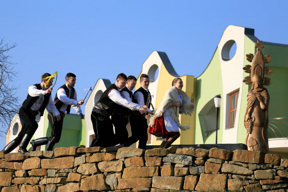 전통의상을 입은 젊은 남성들이 2일(현지시간) 부활절 주간 월요일에 열린 ‘전통 부활절 축제’ 동안 19m의 긴 버드나무 가지로 전통의상을 입은 젊은 여성을 때리는 시늉을 하고 있다. AFP 연합뉴스