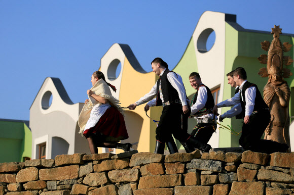 전통의상을 입은 젊은 남성들이 2일(현지시간) 부활절 주간 월요일에 열린 ‘전통 부활절 축제’ 동안 19m의 긴 버드나무 가지로 전통의상을 입은 젊은 여성을 때리는 시늉을 하고 있다. AFP 연합뉴스