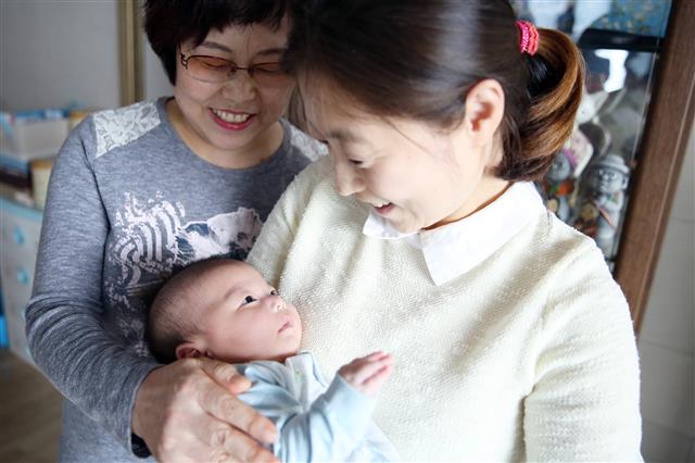 국내 심장이식 환자 중 처음으로 출산에 성공한 이은진(오른쪽)씨가 지난달 9일 광주의 자택에서 아들을 들여다보고 있다. 이씨의 어머니인 김순덕(왼쪽)씨도 심장이식 수술을 받아 이씨의 출산에 큰 힘이 됐다.  서울아산병원 제공