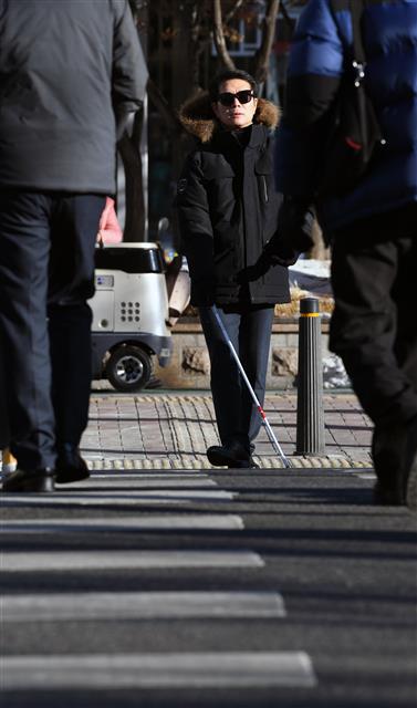 꽃샘추위로 기온이 뚝 떨어진 지난달 22일 시각장애인 체험에 나선 정원오 서울 성동구청장이 흰 지팡이로 바닥을 두드리며 횡단보도를 건너고 있다. <br>강성남 선임기자 snk@seoul.co.kr