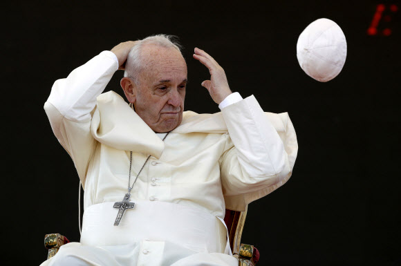 프란치스코 교황이 20일(현지시간) 이탈리아 Alessano에서 Bishop Tonino Bello의 무덤서 ‘제25회 추모식’ 중 기도를 끝내고 돌풍에 모관이 날아가 머리를 감싸쥐며 당황한 모습이 포착되고 있다. AP 연합뉴스