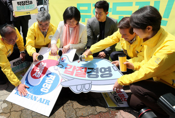 정의당 이정미 대표와 김종민 서울시장 후보, ’땅콩회항’ 피해자인 박창진 사무장 등이 25일 서울 강서구 대한항공 본사 앞에서 열린 정의당 정당연설회에서 대한항공의 황제경영 및 갑질경영을 규탄하며 손팻말에 물을 붓는 퍼포먼스를 하고 있다.  연합뉴스
