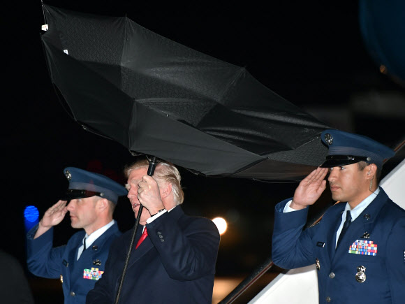 도널드 트럼프 미국 대통령이 28일(현지시간) 미국 워싱턴의 DC 앤드루스 공군 기지에 도착해 미국 대통령 전용기 에어 포스 원에서 내려오고 있는데 강풍에 우산이 뒤집어지고 있다. AFP 연합뉴스