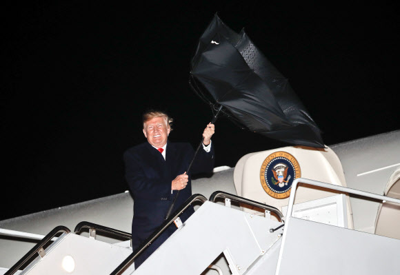 도널드 트럼프 미국 대통령이 28일(현지시간) 미국 워싱턴의 DC 앤드루스 공군 기지에 도착해 미국 대통령 전용기 에어 포스 원에서 내려오고 있는데 강풍에 우산이 뒤집어지고 있다. AP 연합뉴스