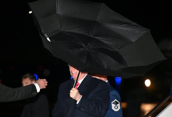 도널드 트럼프 미국 대통령이 28일(현지시간) 미국 워싱턴의 DC 앤드루스 공군 기지에 도착해 미국 대통령 전용기 에어 포스 원에서 내려오고 있는데 강풍에 우산이 뒤집어지고 있다. AFP 연합뉴스